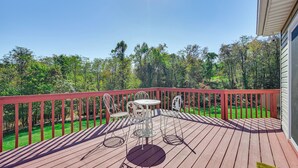 A wooden deck with a red railing, a table, and four chairs. - Private Deck: Berkeley Springs Getaway! (Berkeley Springs)