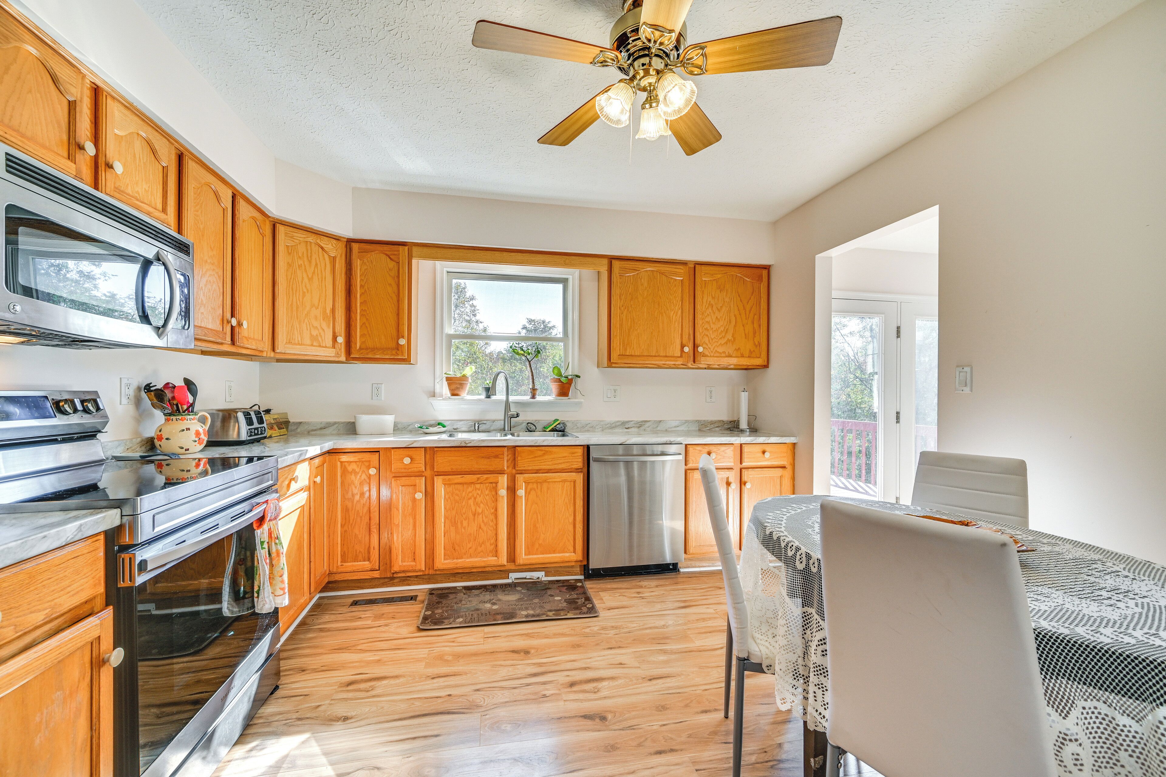 A kitchen with wooden cabinets, stainless steel appliances, and a ceiling fan.