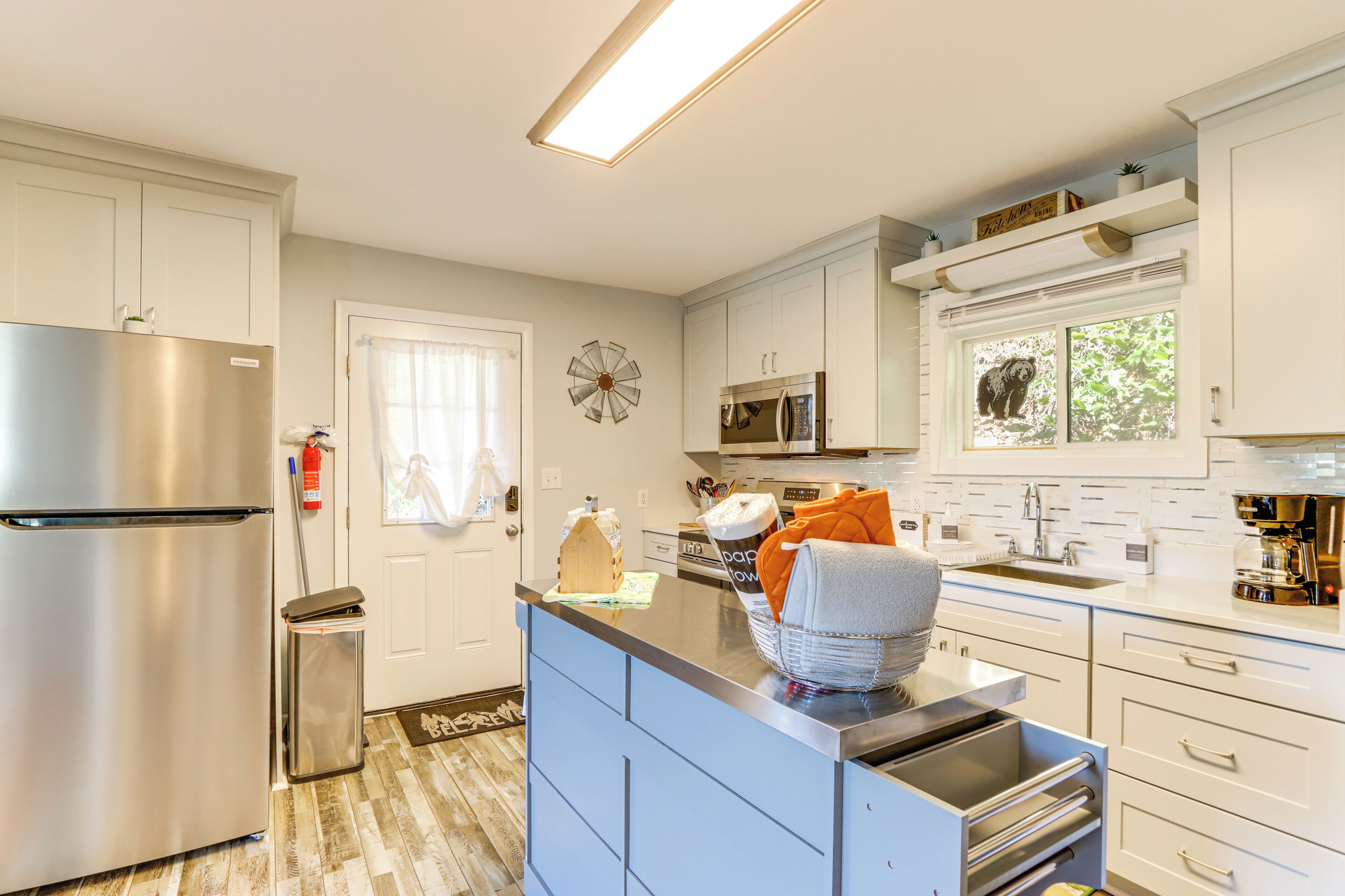 A modern kitchen with white cabinets, stainless steel appliances, and a blue island.