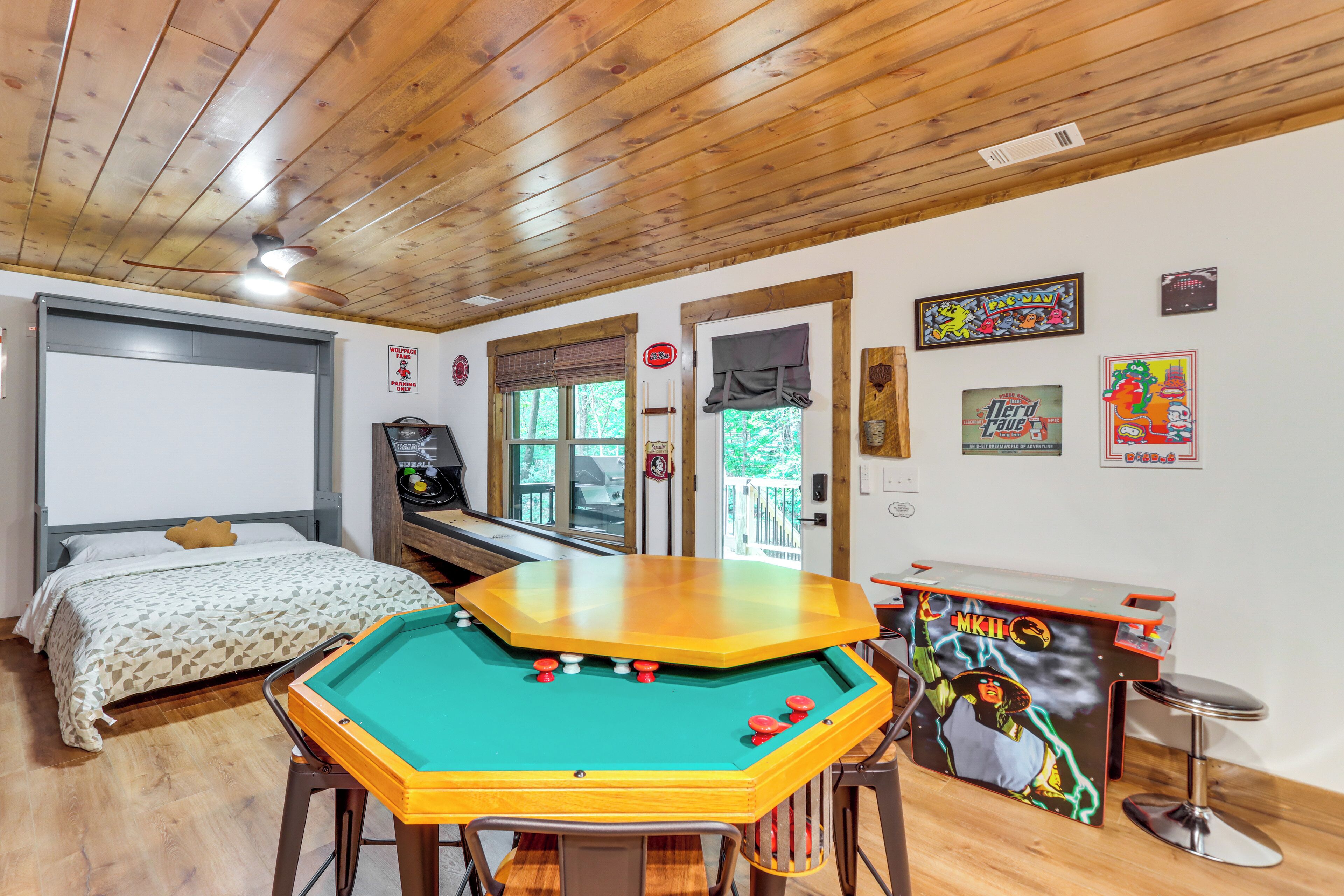 A room with a pool table, a bed, a desk with a computer, and various posters on the wall.