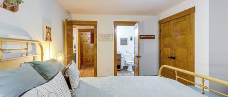 A bedroom with a bed, a wooden door, a ceiling fan, and a wall-mounted light fixture.