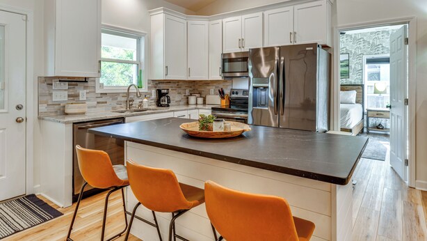 A modern kitchen with white cabinets, stainless steel appliances, and a central island with bar stools. - Waterfront Lake Hickory Retreat w/ Private Dock! (Hickory)