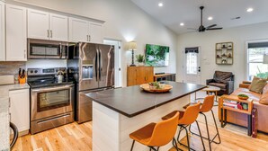 A modern kitchen with stainless steel appliances, a wooden island with bar stools, and a seating area with a sofa and chairs. - Waterfront Lake Hickory Retreat w/ Private Dock! (Hickory)