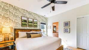 A bedroom with a large bed, wooden headboard, a ceiling fan, and a patterned wallpaper. - Waterfront Lake Hickory Retreat w/ Private Dock! (Hickory)