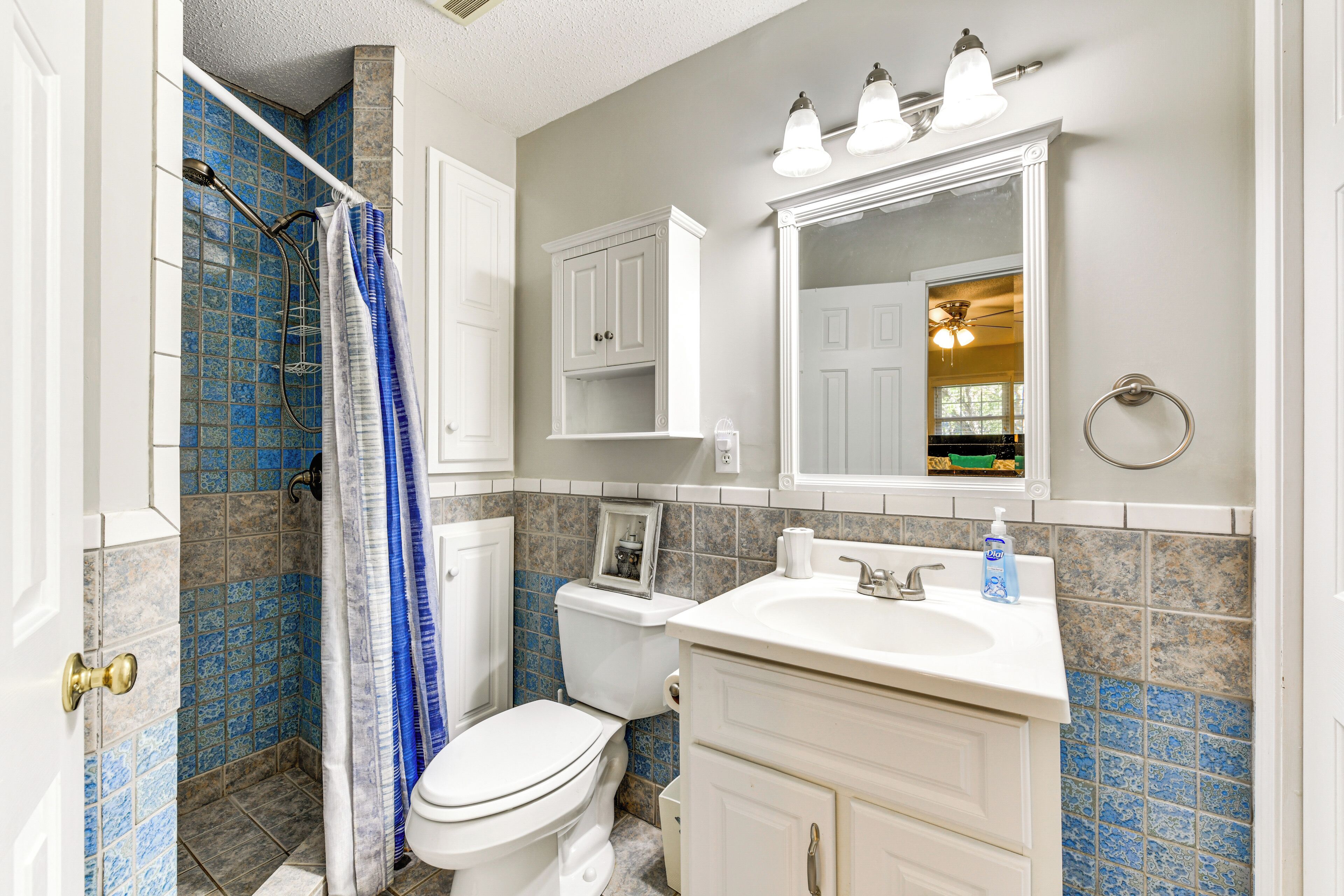 Une salle de bain équipée d’une douche, de toilettes, d’un lavabo et de meubles de rangement.