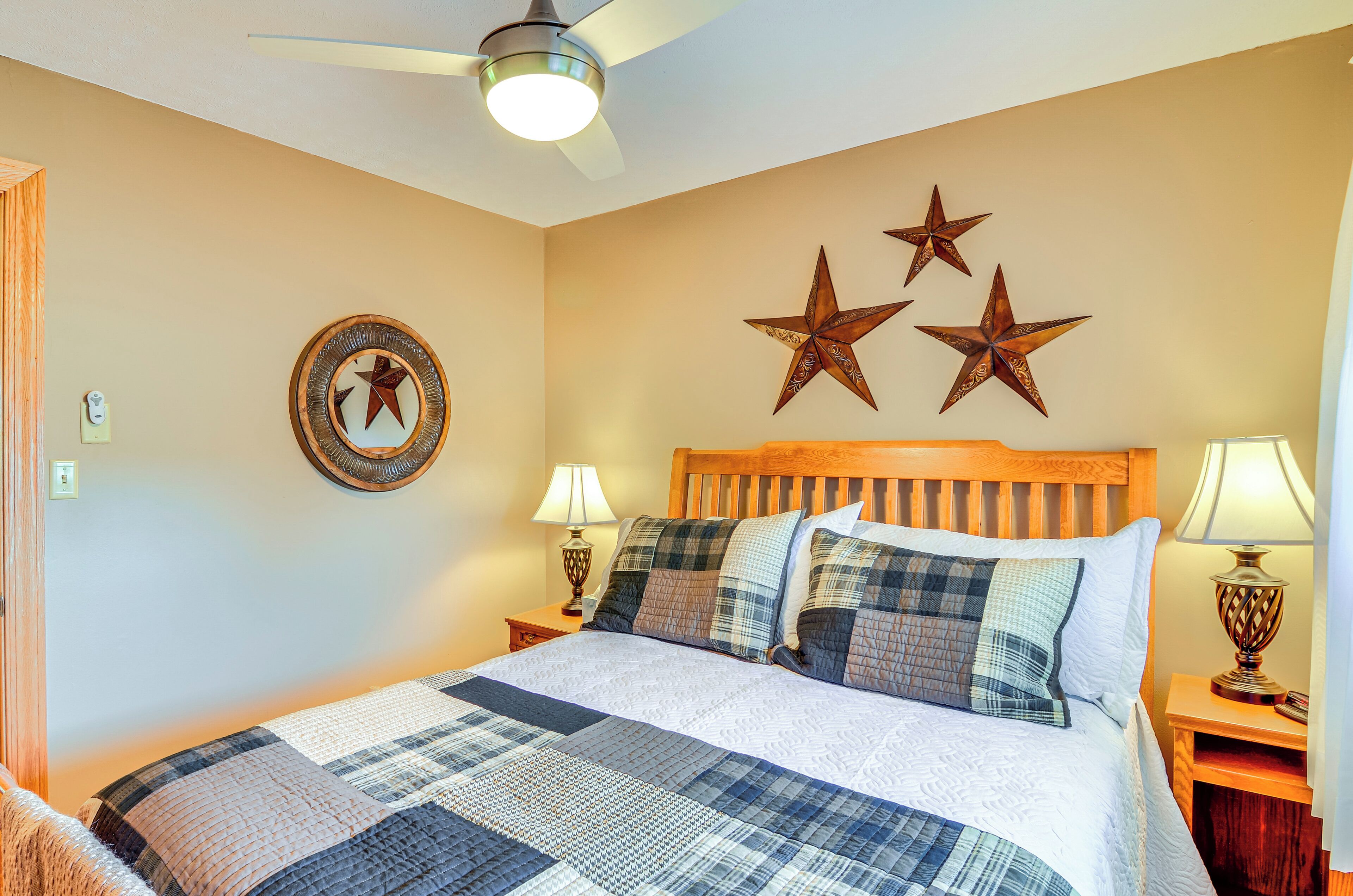 A bedroom with a large bed, wooden headboard, and three wall-mounted stars. There are two bedside tables with lamps.