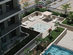 Relax by the rectangular pool surrounded by lounge chairs and a shaded area.