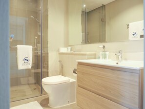 Enjoy a refreshing shower in the bathroom, featuring a glass-enclosed shower area, a toilet, and a vanity with a cabinet.