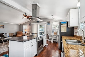 A modern kitchen with a central island, stainless steel appliances, and a dining area with a view.