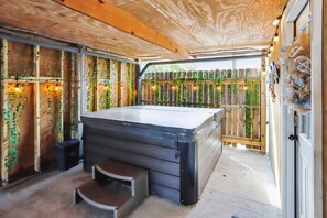 Uma banheira de hidromassagem com degraus, cercada por paredes de madeira e um cercado de madeira com plantas.