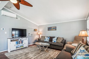 A living room with a flat-screen TV, a sofa, a coffee table, and a lamp.