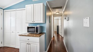 A kitchen with white cabinets, a microwave, and a granite countertop. - Sea Glass Shack -- Pet Friendly with Hot Tub (Kill Devil Hills)