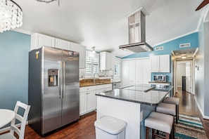 Una cocina moderna con armarios blancos, electrodomésticos de acero inoxidable y una isla central.