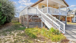 A two-story house with a wooden staircase and a balcony. - Sea Glass Shack -- Pet Friendly with Hot Tub (Kill Devil Hills)
