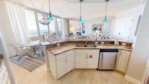 A modern kitchen with granite countertops, white cabinetry, and a built-in dishwasher.