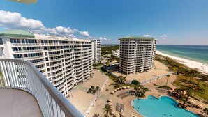 A high-rise hotel with multiple balconies, a pool area, and a beach view.