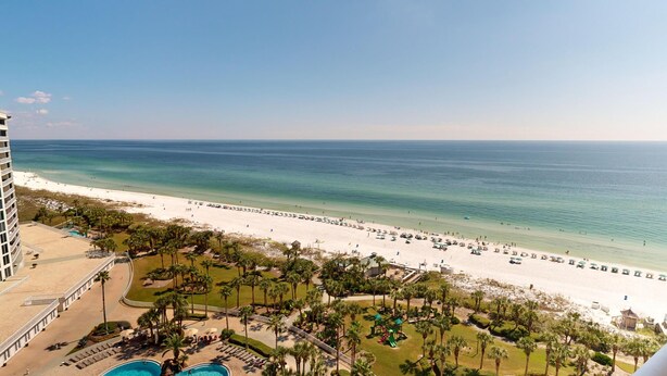 A resort with a beach view, a pool area, and palm trees.