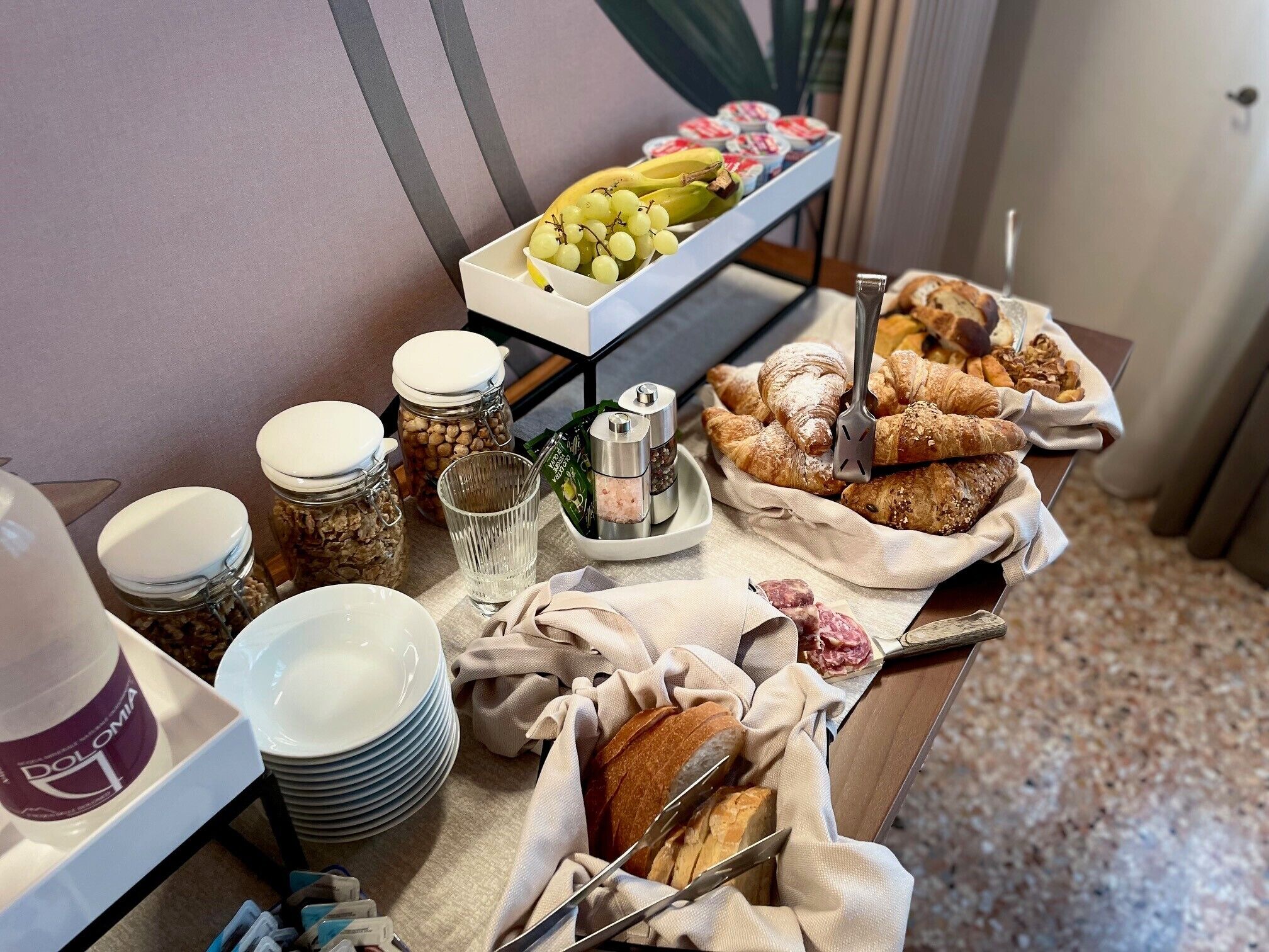 A buffet table with various food items including bread, pastries, and fruits.