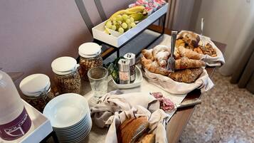 A buffet table with various food items including bread, pastries, and fruits.