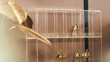 A clear plastic display case with numbered compartments, each holding a small golden bell with a hotel name.