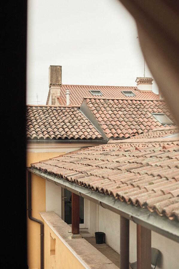 A view of terracotta-tiled roofs and a balcony with a trash bin.