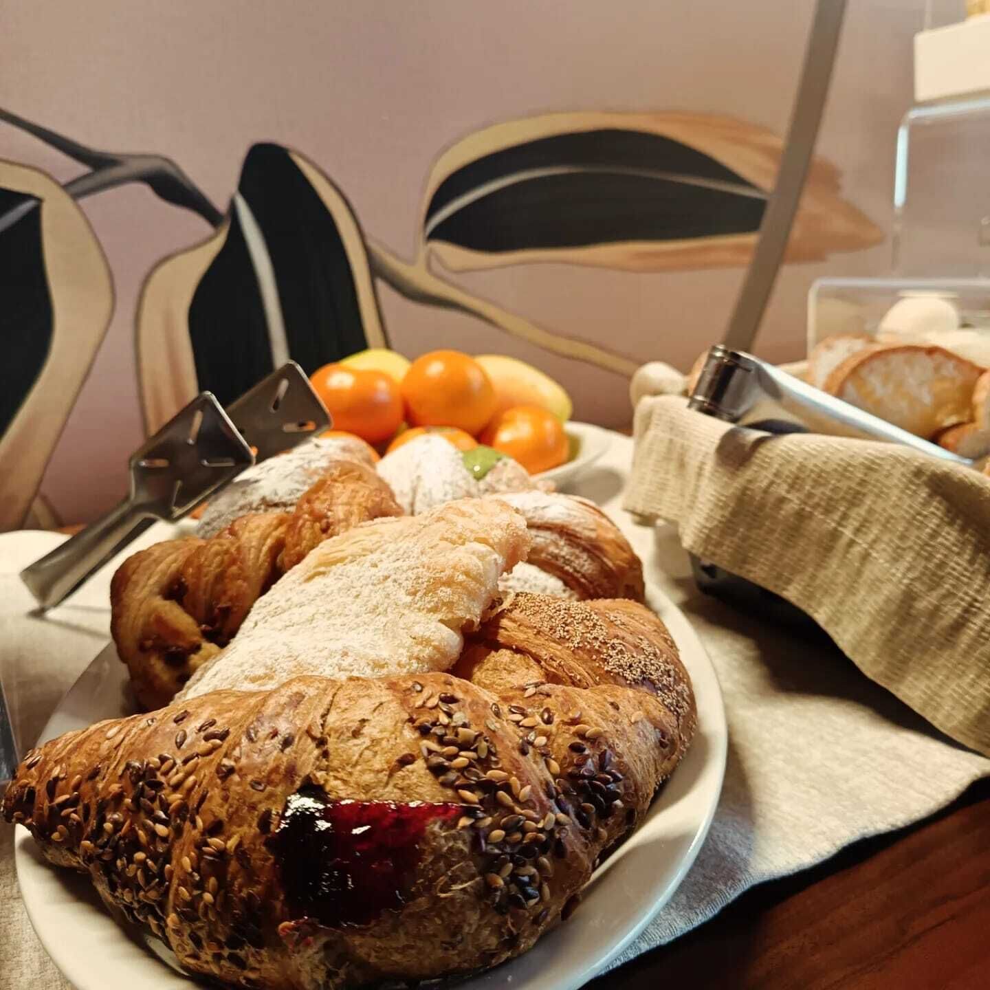 Une assiette contenant divers pâtisseries, un saladier rempli de fruits et un récipient en métal, le tout posé sur une table.
