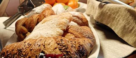 Une assiette contenant divers pâtisseries, un saladier rempli de fruits et un récipient en métal, le tout posé sur une table.