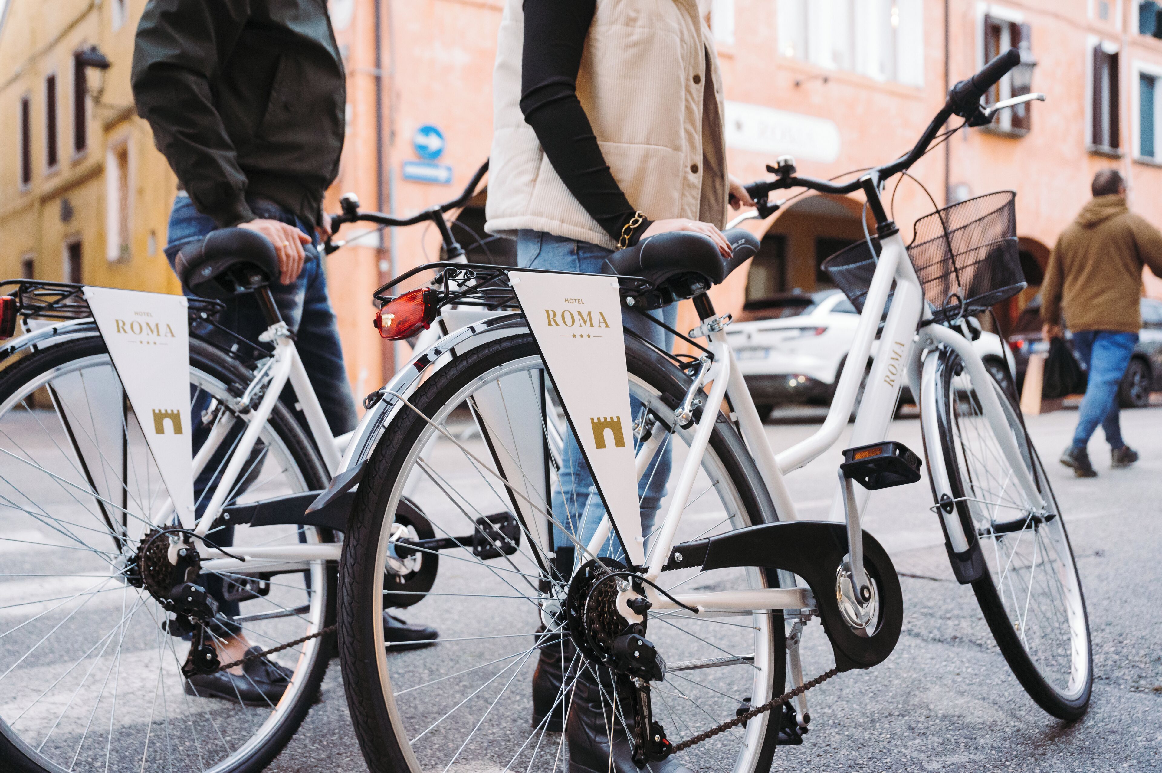 Two bicycles with "HOTEL ROMA" signage, parked on a city street.