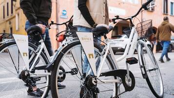 Two bicycles with "HOTEL ROMA" signage, parked on a city street.