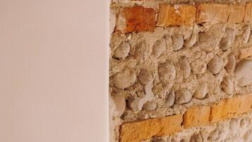 A close-up of a wall with a textured stone and brick pattern, a metallic door handle, and a white door frame.