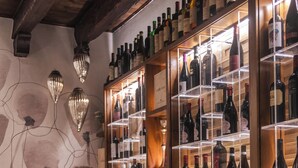 Interior de restaurante con paredes de madera, una vitrina de vinos y mesas dispuestas para comer.