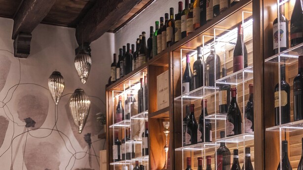L’intérieur d’un restaurant, avec des murs en bois, un présentoir à vins et des tables dressées pour le service.