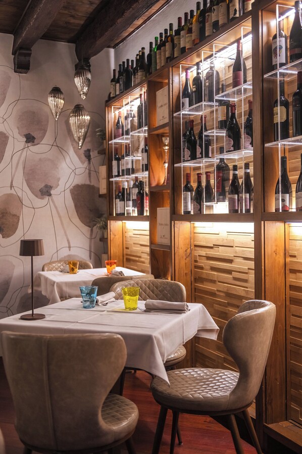 L’intérieur d’un restaurant, avec des murs en bois, un présentoir à vins et des tables dressées pour le service.