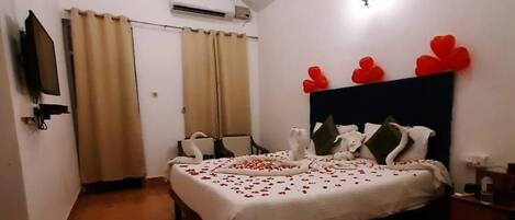 A bedroom with a bed, a ceiling fan, a TV, and a wall-mounted air conditioner.