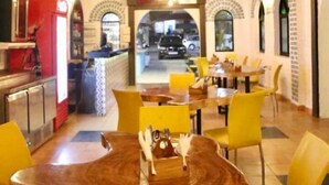 A restaurant with a rustic wooden ceiling, yellow chairs, and a central round table. - tio carmino resort (Calangute)