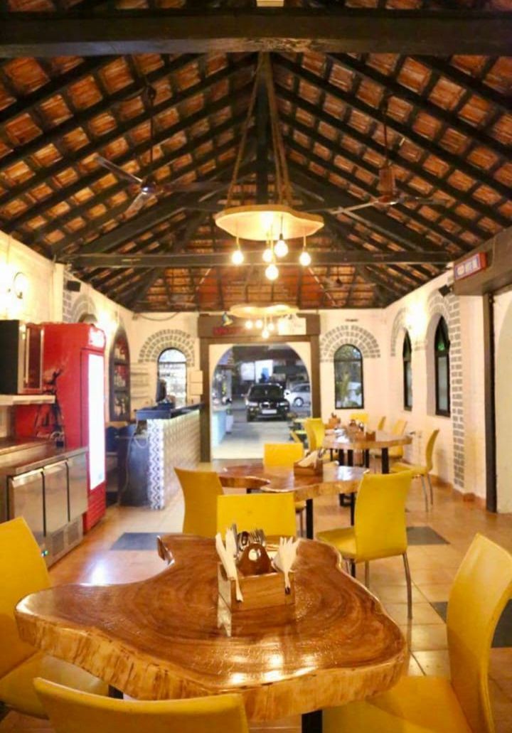 A restaurant with a rustic wooden ceiling, yellow chairs, and a central round table.