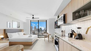A modern hotel room with a bed, a small dining area, a kitchen with a microwave, and a view of the city. - Bright Studio | Concierge | Near Miami Worldcenter (Miami)