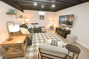 Ein Wohnzimmer mit einer Couch, einem Fernseher, einem Schachbrettmuster-Teppich und einem Holztisch.