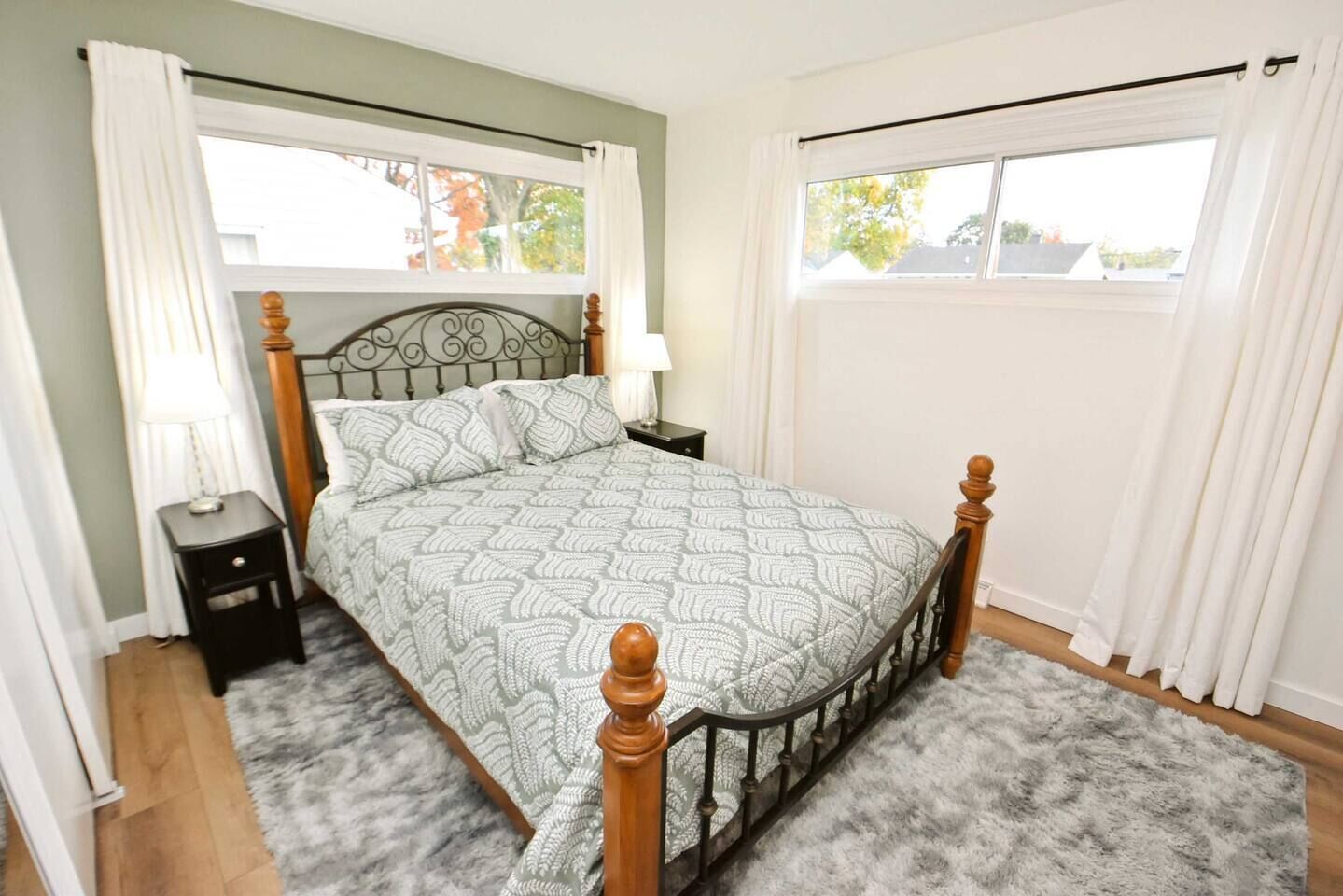 A bedroom with a bed, nightstands, a lamp, and a window with curtains.