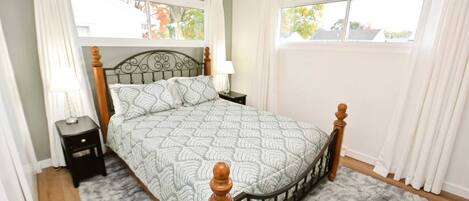 A bedroom with a bed, nightstands, a lamp, and a window with curtains.