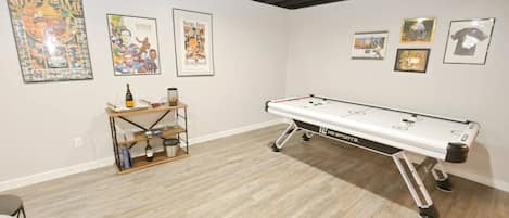 A room with a pool table, framed sports memorabilia on the walls, and a small shelf with items.