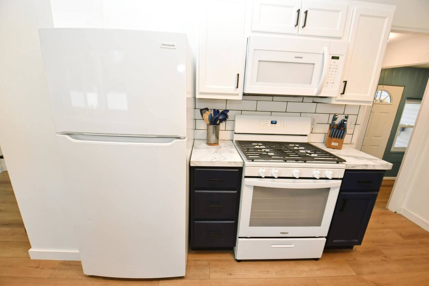 A kitchen with a white refrigerator, a stove, and a microwave.