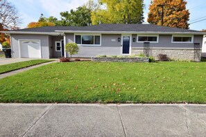 A single-story house with a garage, a small front yard, and a stone foundation.
