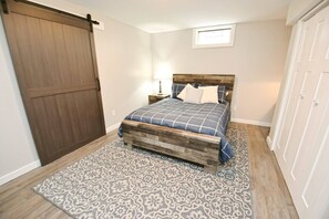 Une chambre à coucher comprenant un lit, une table de chevet, une lampe, un tapis à motifs, une porte coulissante et un placard.