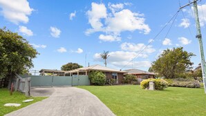 A residential property with a paved driveway leading to a gated entrance, surrounded by well-maintained lawns and mature trees. - The Hideaway: This holiday house is your gateway to unforgettable memories (Paynesville)