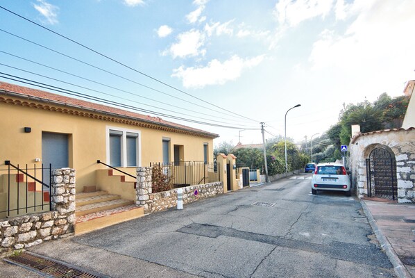 A residential street with a yellow building, stone steps, and a parked car.