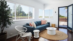 Una sala de estar moderna con un sofá azul, una butaca de mimbre blanco y una mesa de centro redonda.