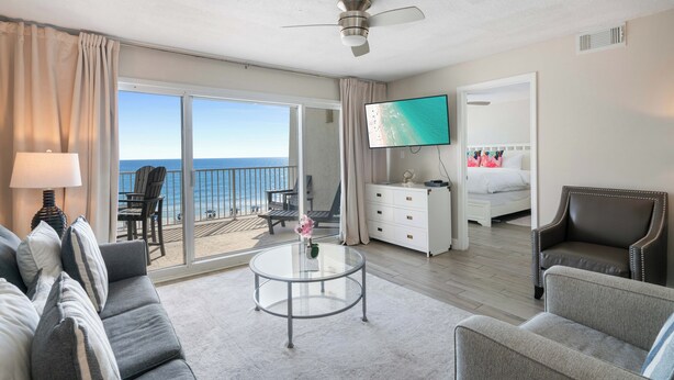 A hotel room with a balcony, a bed, a TV, a desk, and a sofa.