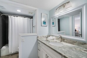 Un baño moderno con ducha, un espejo grande y encimera de mármol.