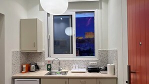 Een compacte keuken met een inbouwkoelkast, een spoelbak en een raam met uitzicht op een historisch gebouw 's nachts.